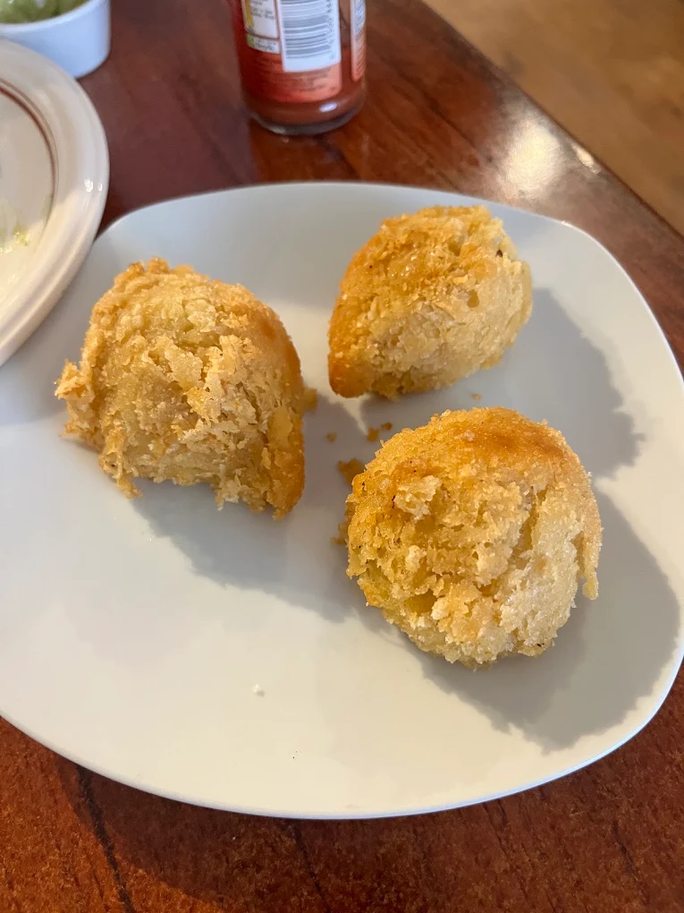Three golden coxinhas — teardrop-shaped chicken croquettes — on a white plate.